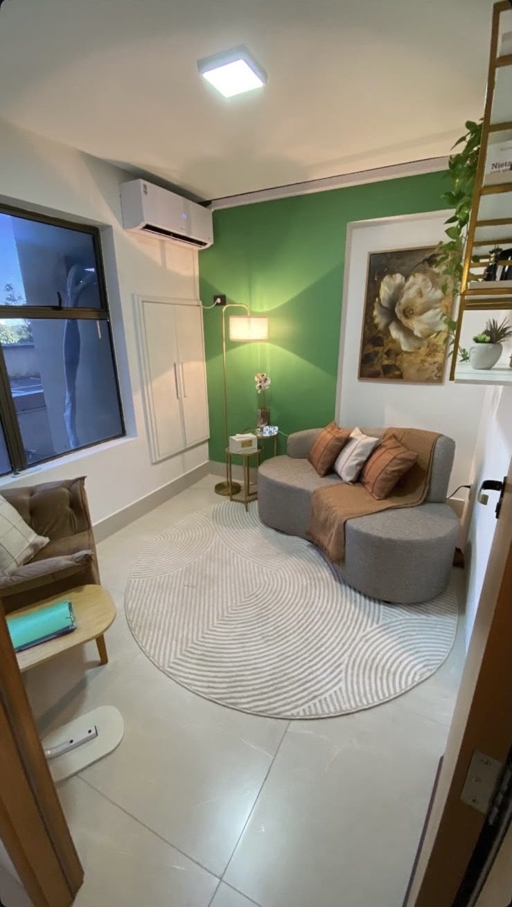 Sala de atendimento com sofá, tapete redondo e brinquedos.